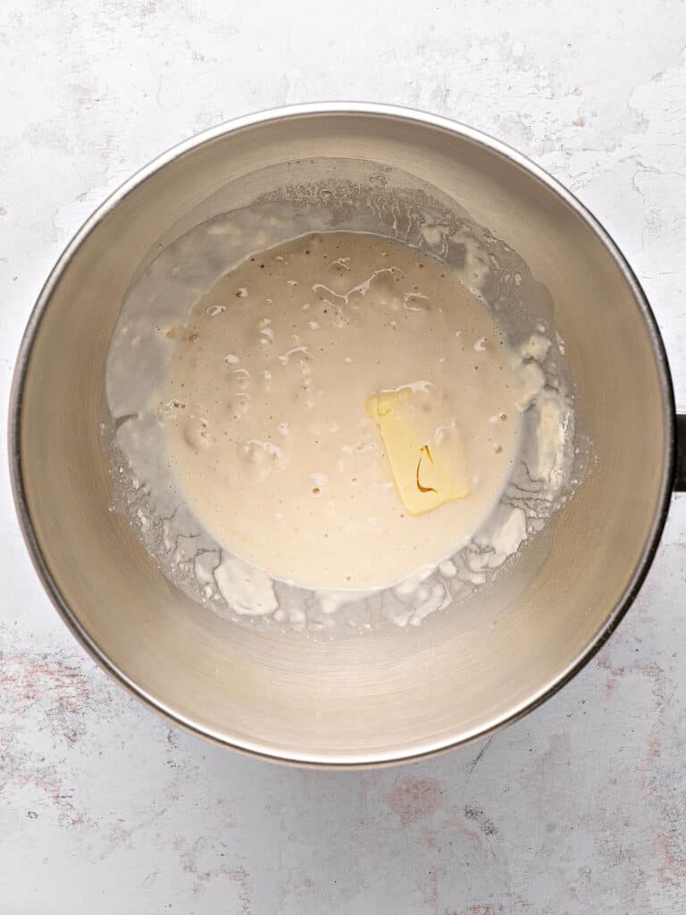 Yeast mixture in a metal bowl. Light gray background.