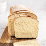 Sliced white sandwich bread on a wooden board. Light gray background.