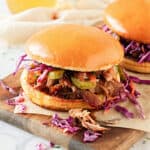 Close up pulled pork coleslaw pickle sandwich on burger bun. Wooden board.