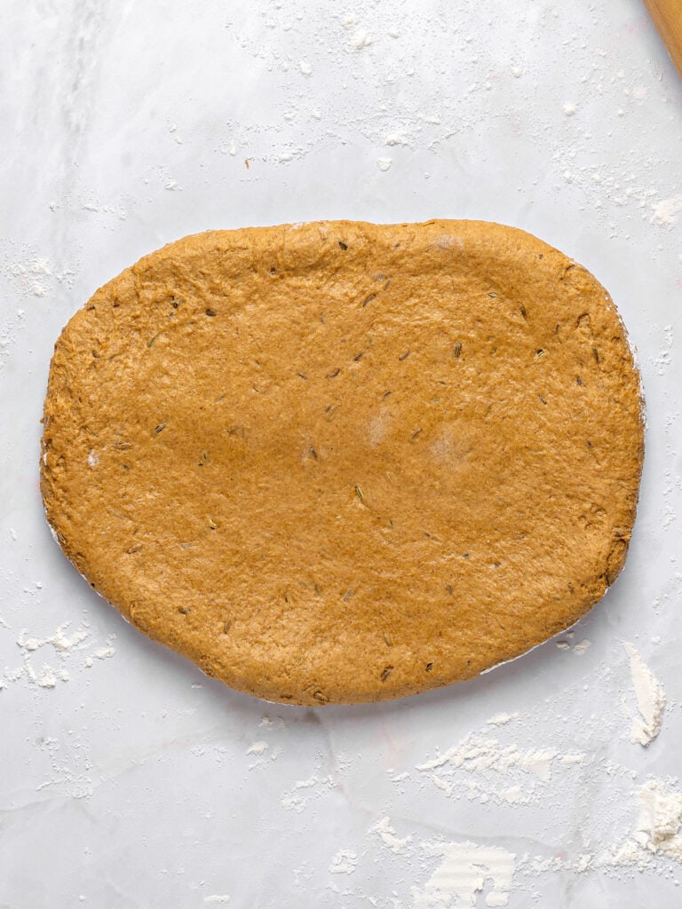Rolled rye bread dough on a light gray surface.