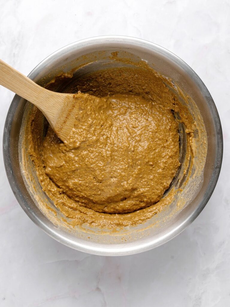 Dark rye bread mixture in a metal bowl. Light gray background.