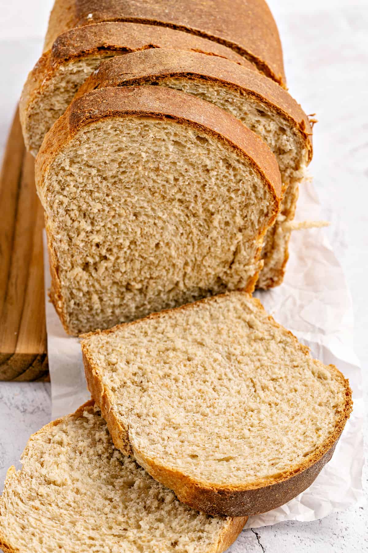 Sliced whole wheat sandwich bread on a white background.
