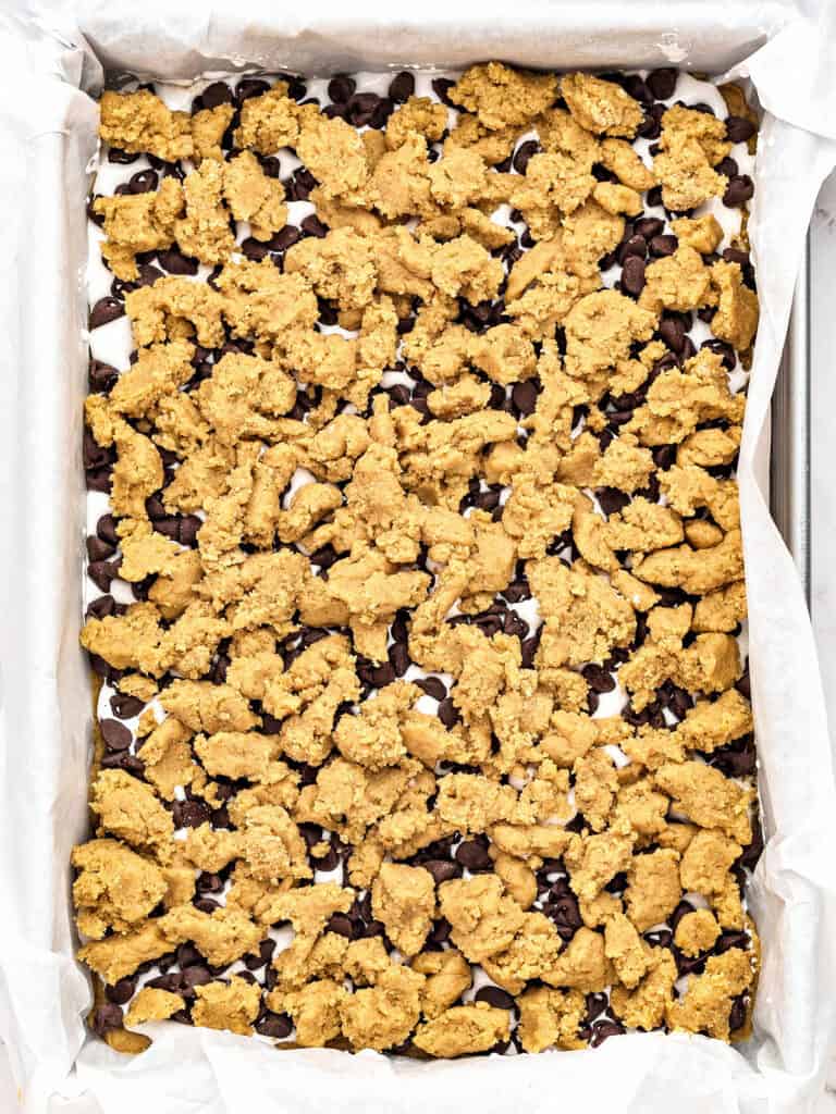 Unbaked brown sugar shortbread topped s'mores bars in a rectangular pan.