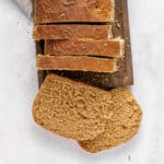 Wooden board and white background with sliced rye sandwich bread loaf.
