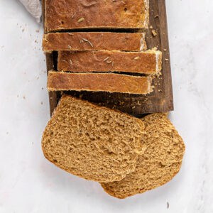 Wooden board and white background with sliced rye sandwich bread loaf.