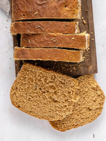 Wooden board and white background with sliced rye sandwich bread loaf.