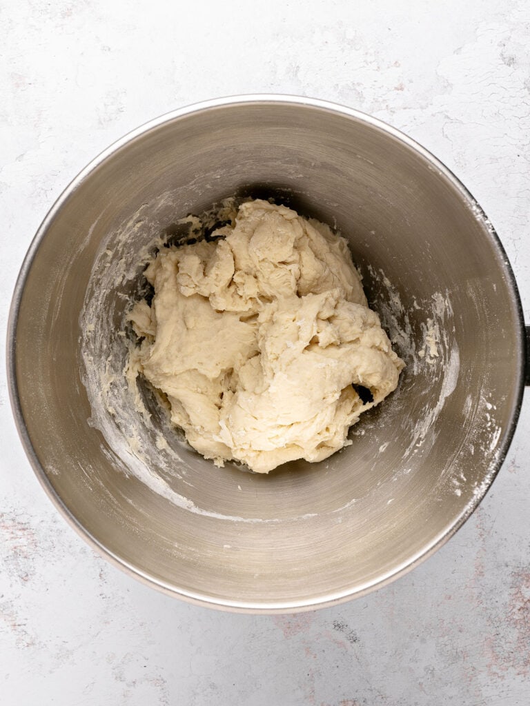 Shaggy white dough in a metal bowl. Light gray background.
