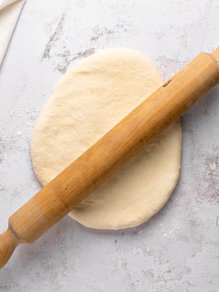 Rolled white bread dough. Light gray background. Rolling pin.