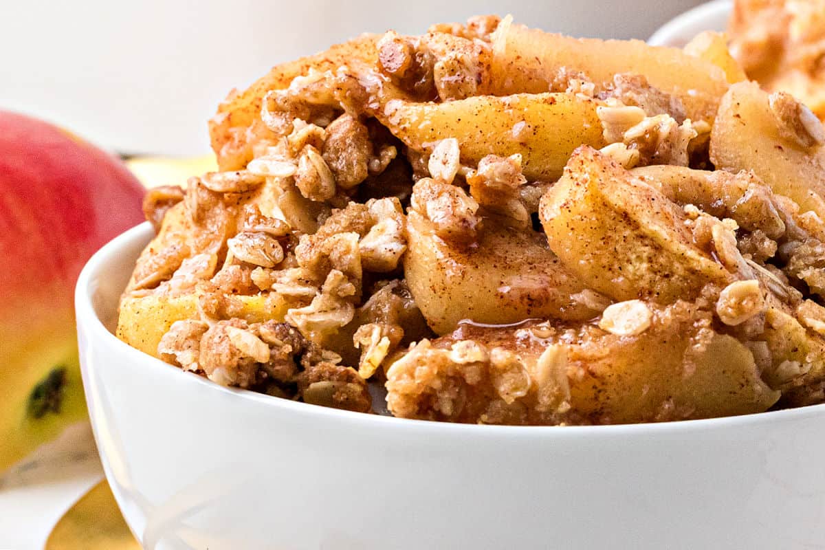 Serving of apple crisp in a white bowl.