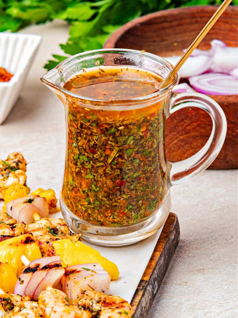 Glass jar with chimichurri. Shrimp skewers, onion, parsley.