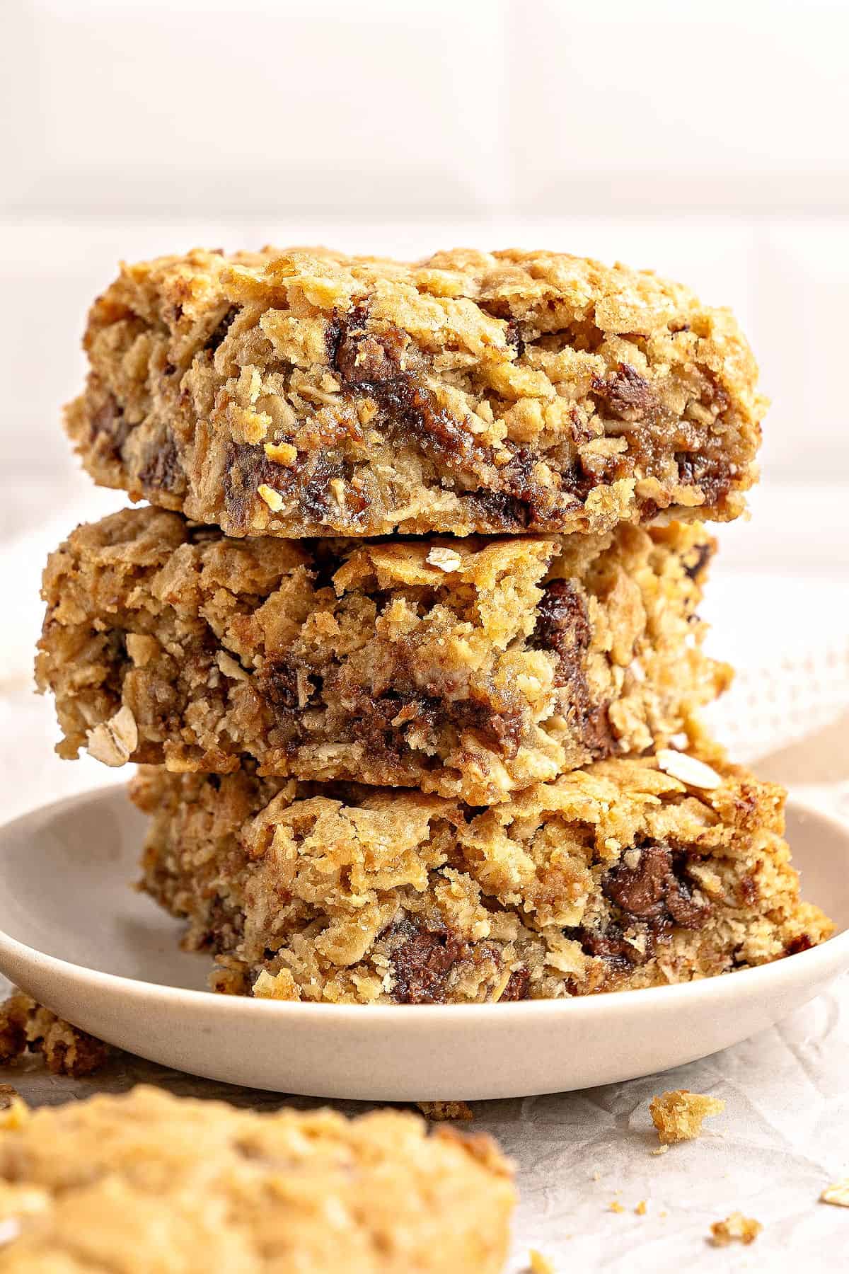 Three stacked oatmeal chip bars on a white plate. Tile background.