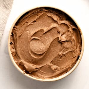 Beige bowl with chocolate frosting. White background. Top view.