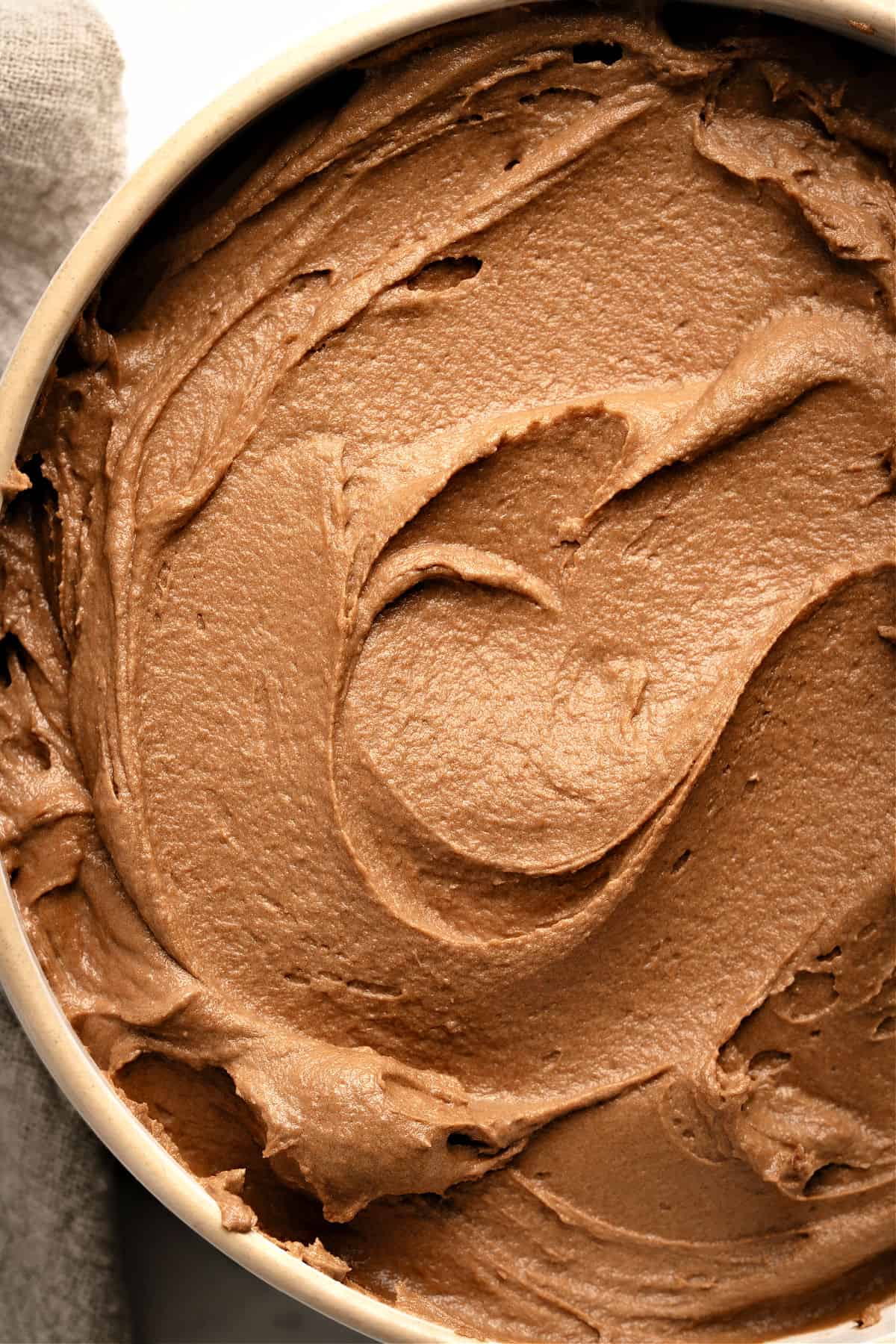 Close up chocolate frosting in a beige bowl. Partial view.