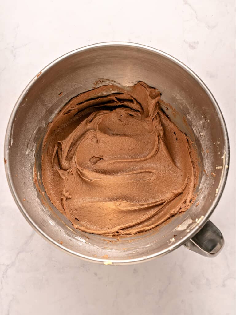 Metal bowl with chocolate frosting. White background.