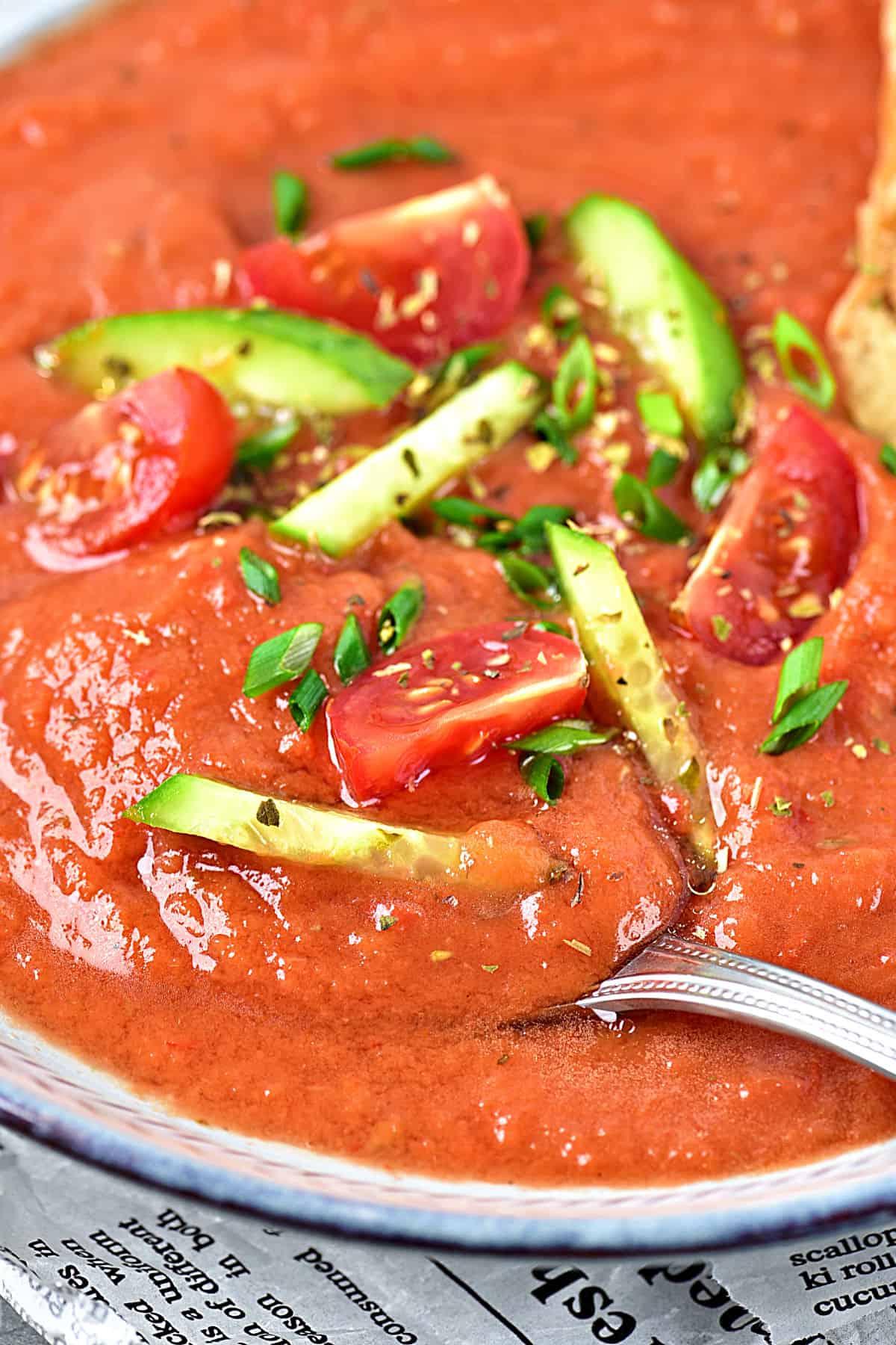 Close up gazpacho with cucumber and tomato garnish.