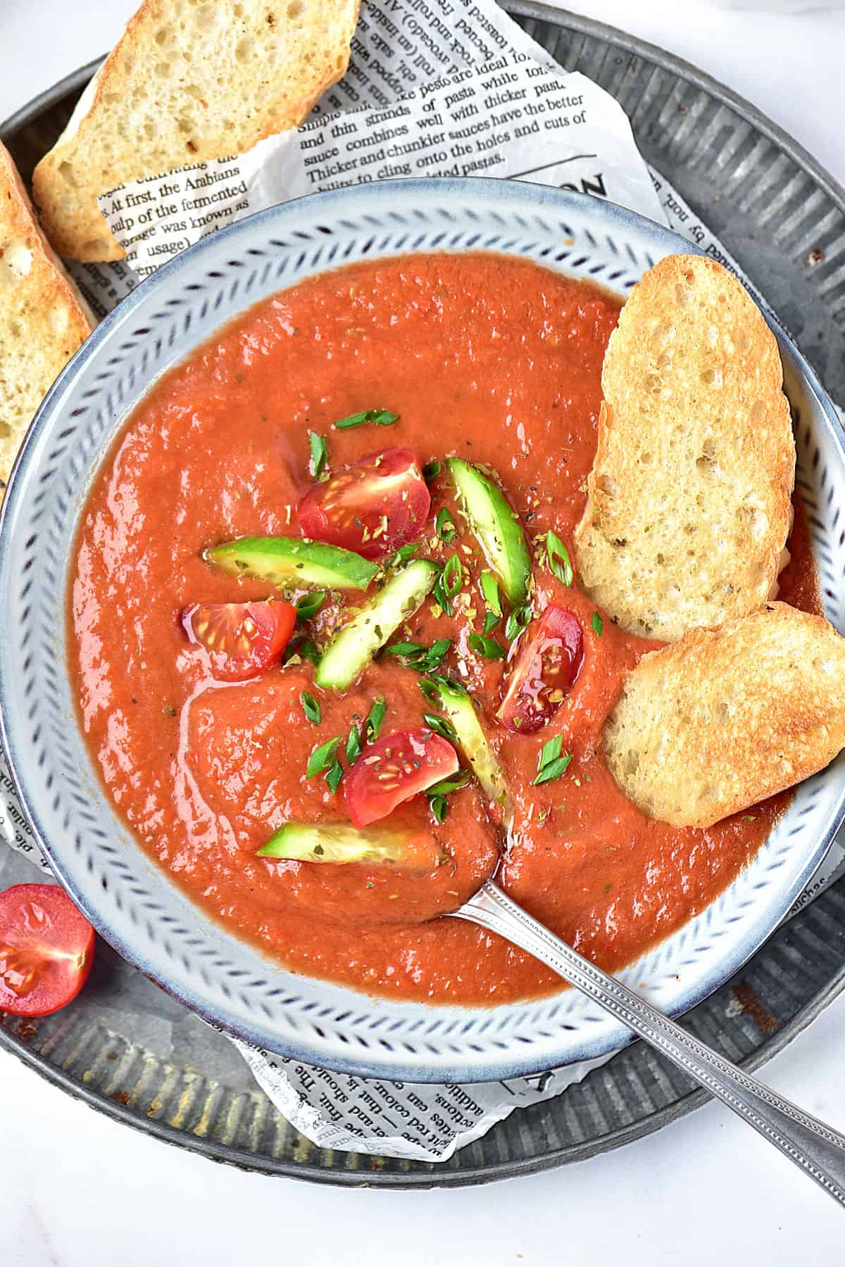 Spanish gazpacho soup bowl and toasted bread on a metal tray.