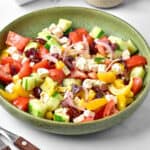 White background with green plate of Greek salad.
