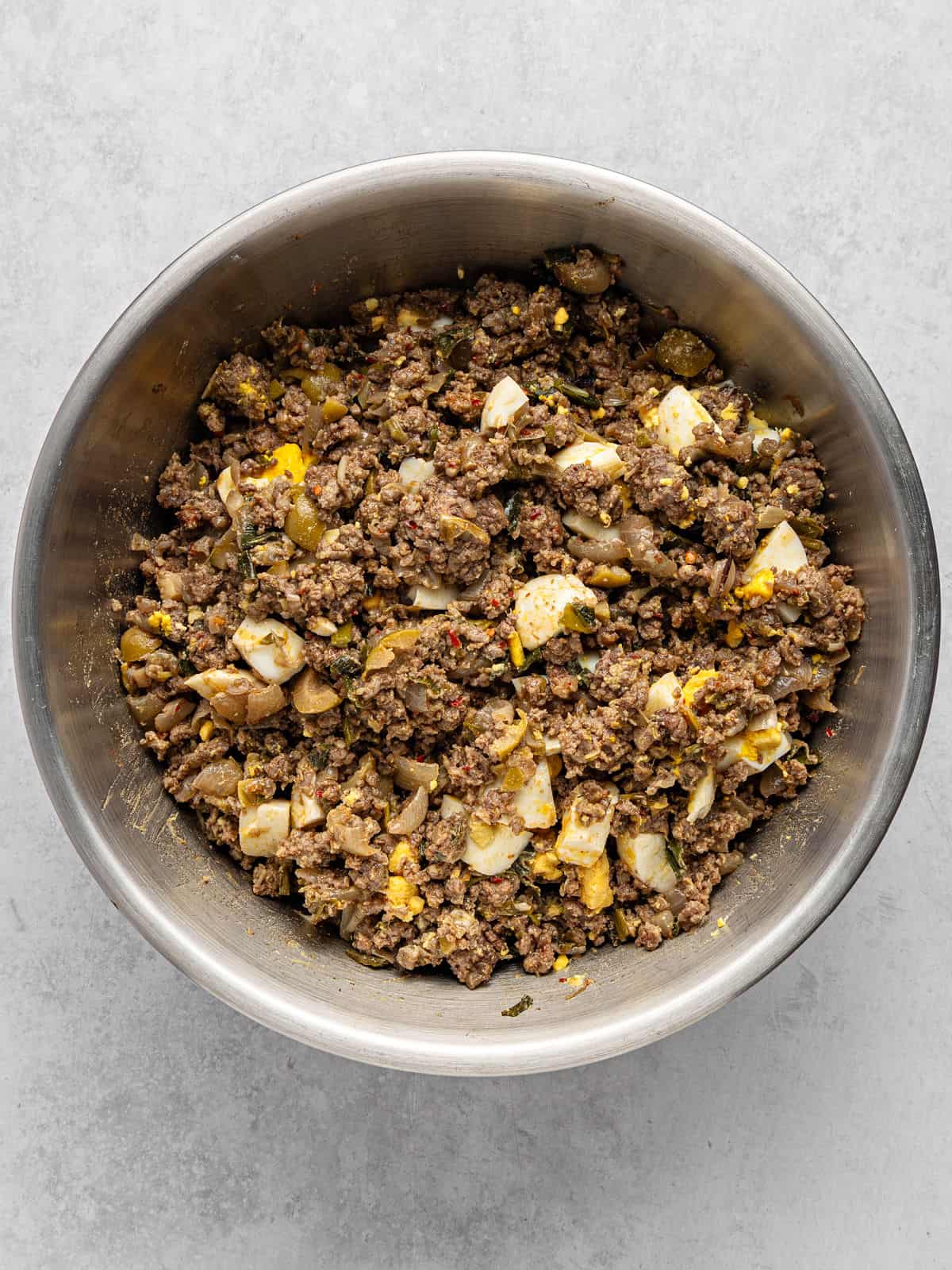 Metal bowl with beef picadillo filling for empanadas.