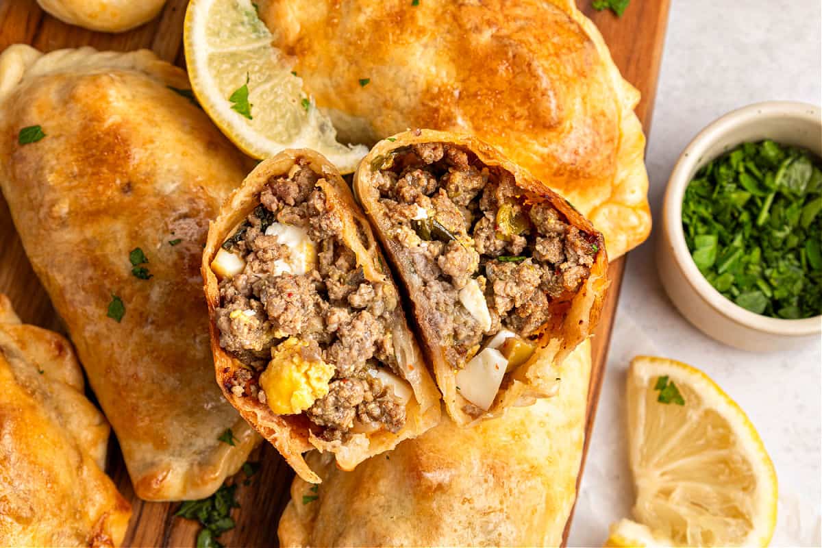 Halved beef empanada on a pile of whole ones.