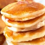 Turquoise, brown and white text overlay on stack of syrupy pancakes.