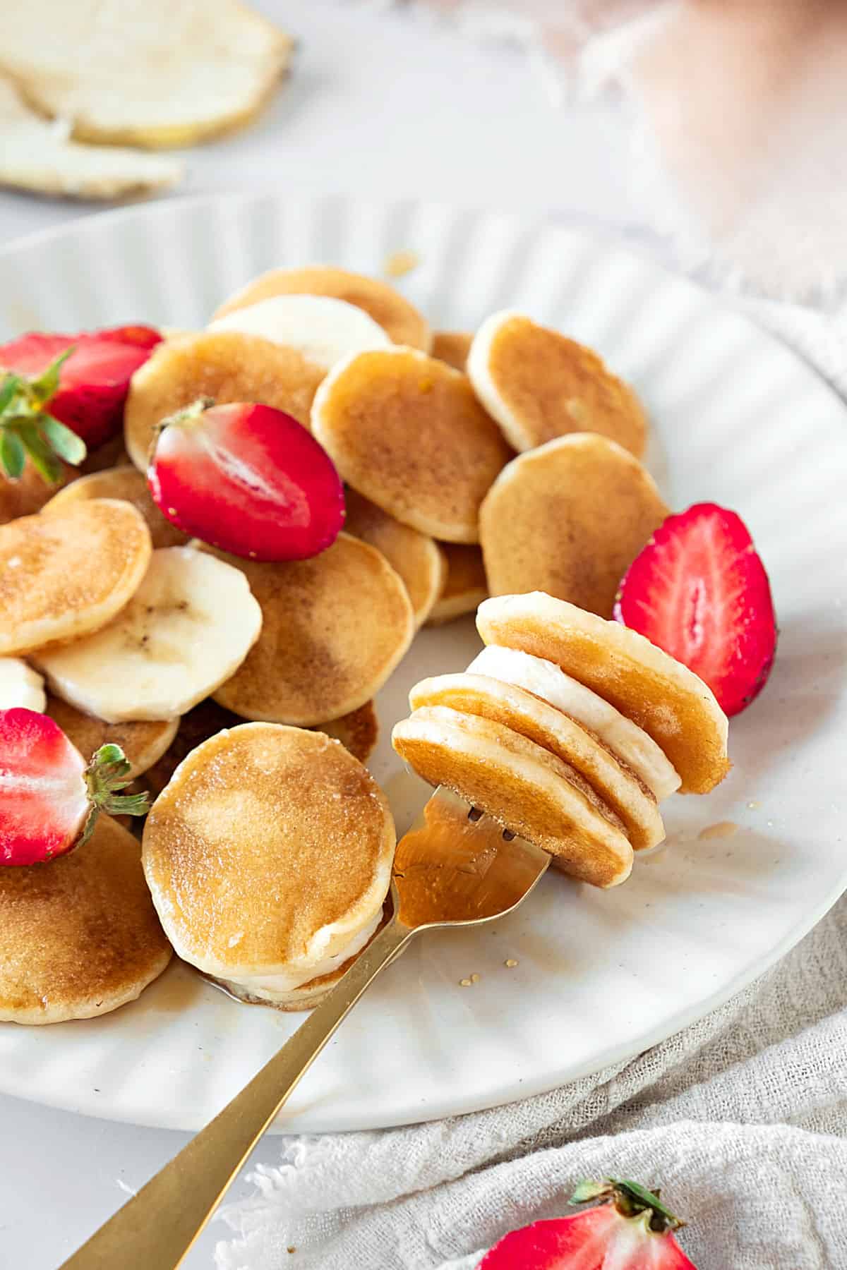White plate with mini pancakes and berries. Silver fork.