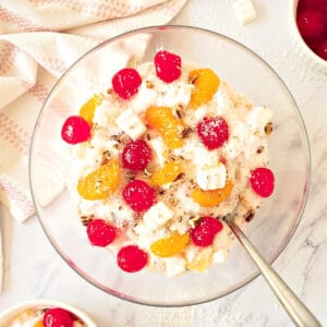 Top view of glass bowl with colorful ambrosia salad. White background.