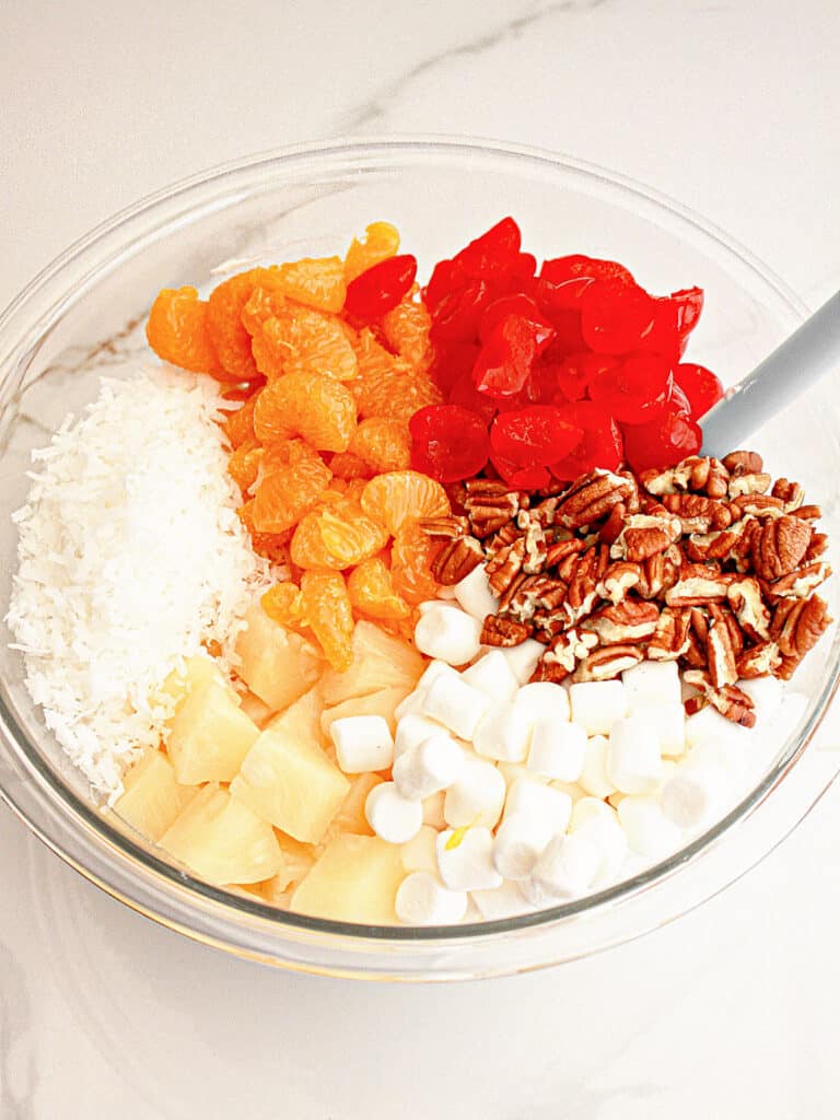 Chopped ingredients for ambrosia salad in a glass bowl.