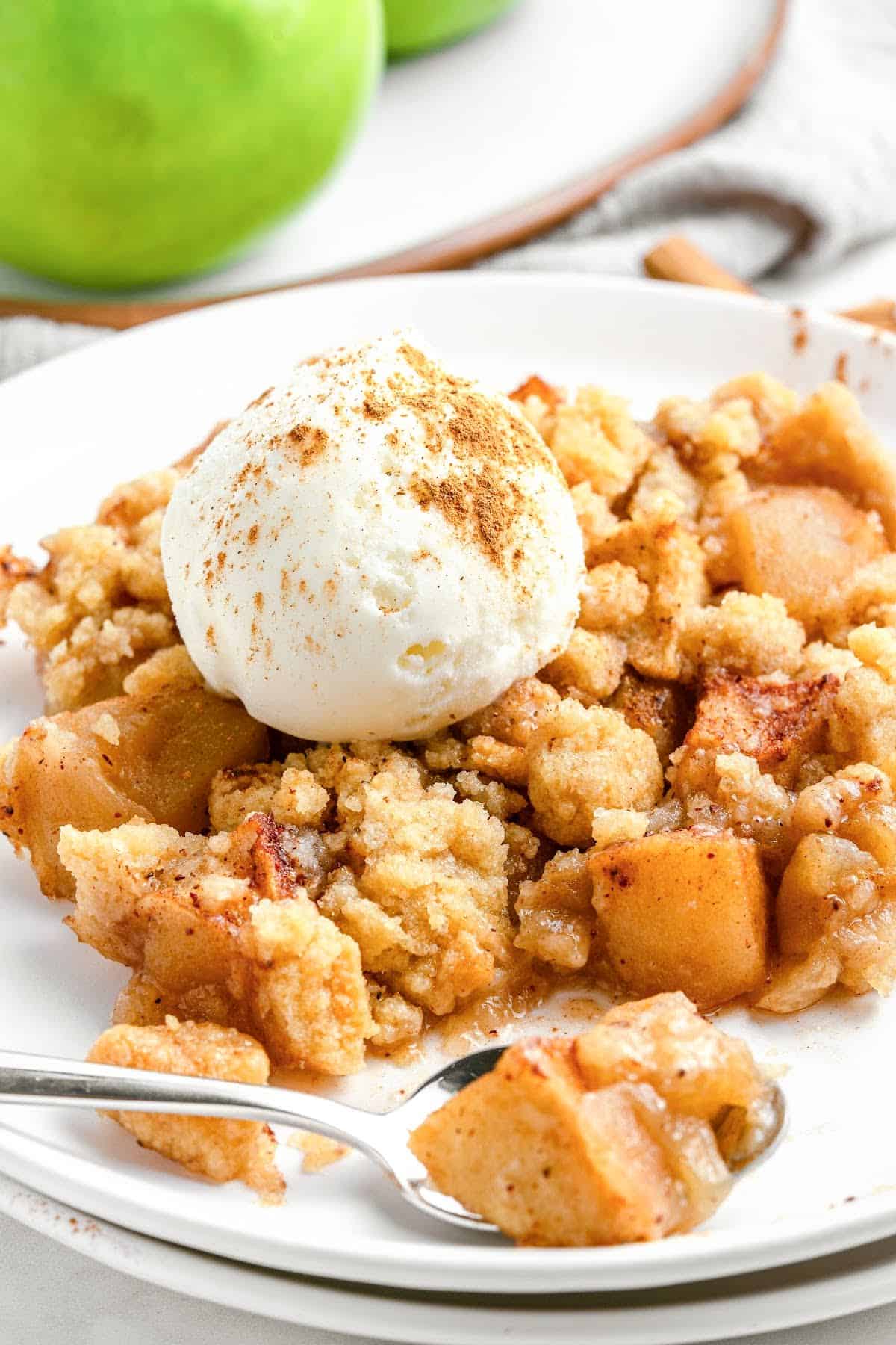Apple crumble serving on a white plate with scoop of ice cream.
