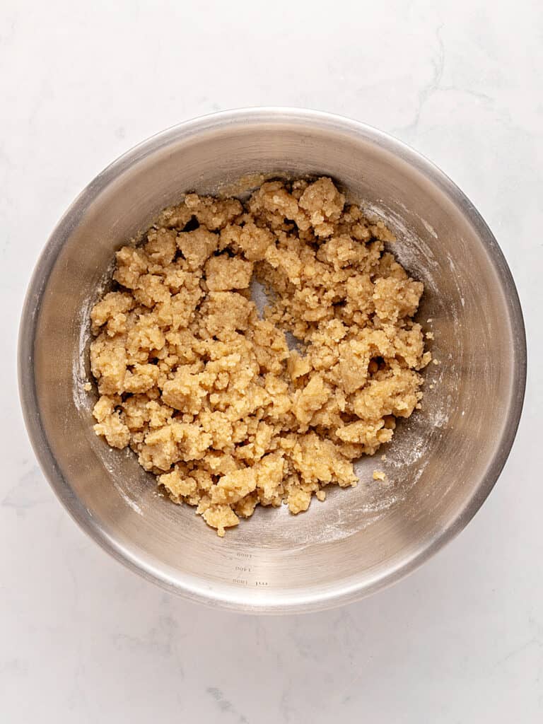 Metal bowl with crumble mixture. Whitish background.