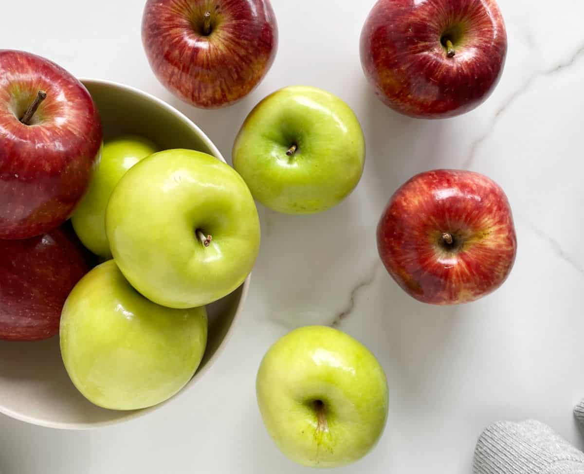 Green and red apples on white marble.