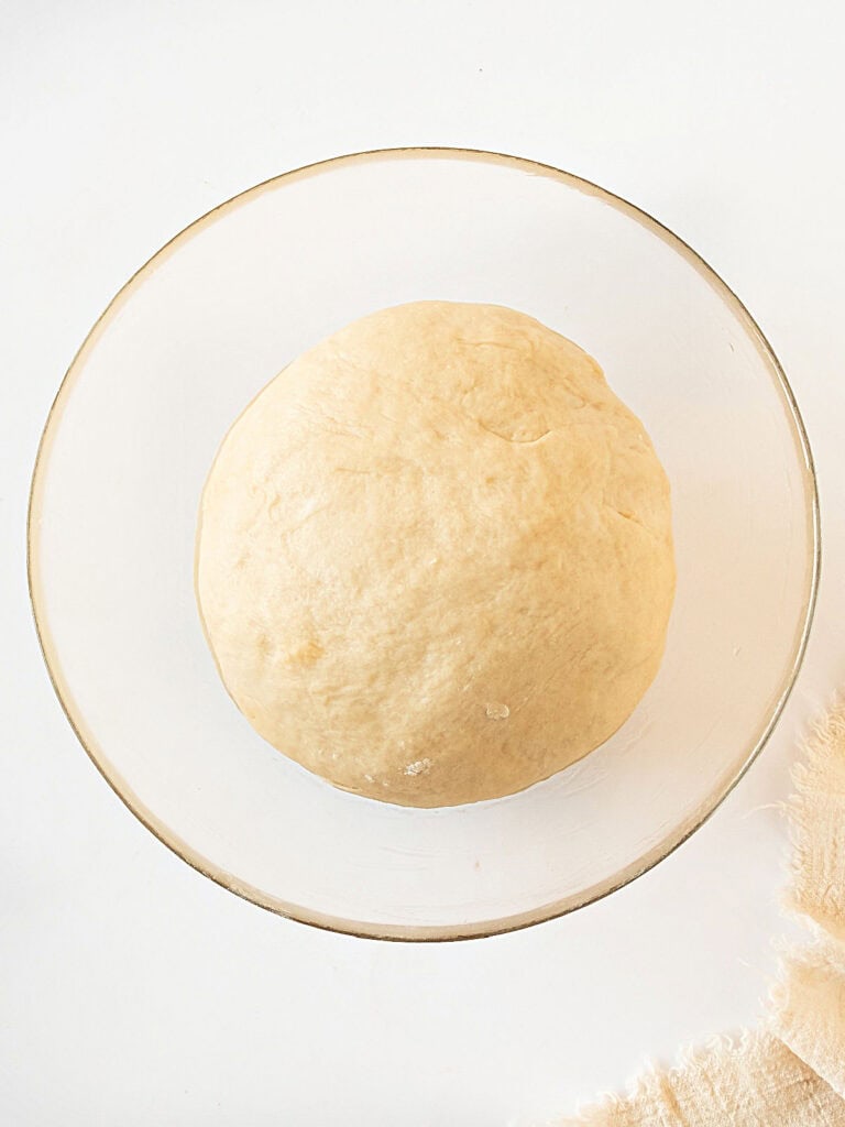 Bread dough in a glass bowl. White background.