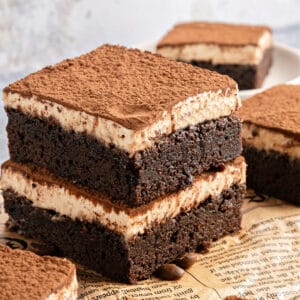 Yellow newspaper sheet beneath stack of two tiramisu brownies.