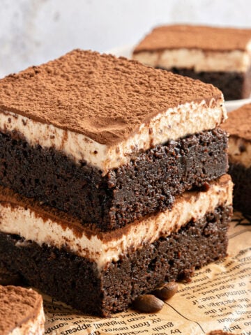 Yellow newspaper sheet beneath stack of two tiramisu brownies.
