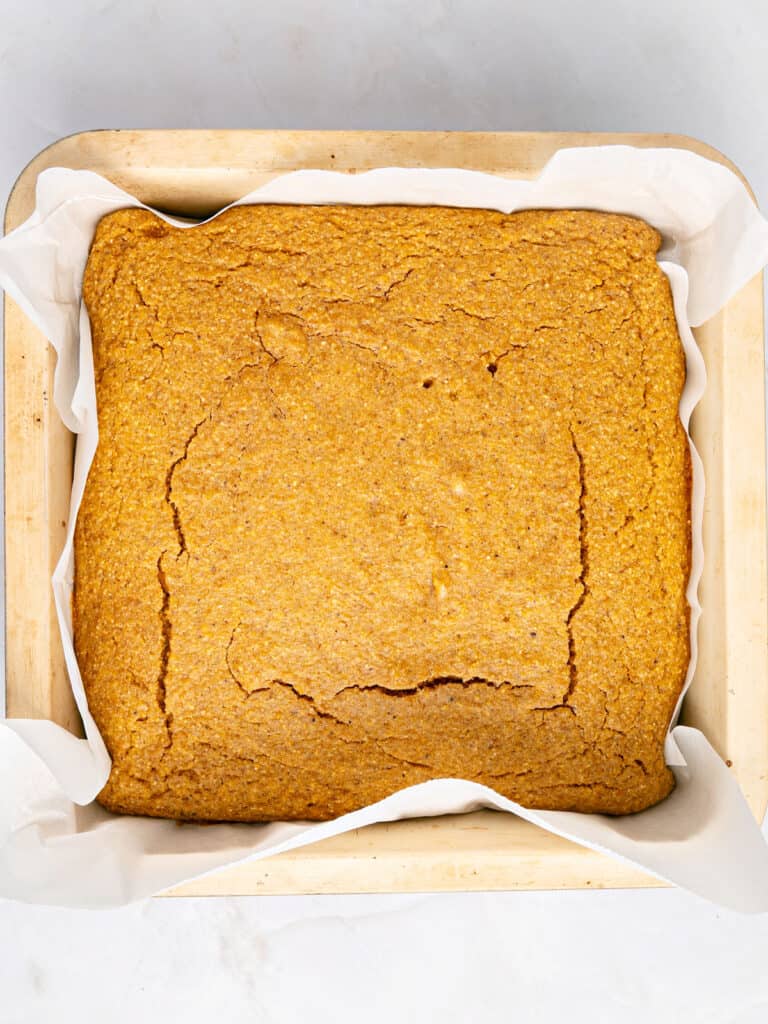 Baked sweet potato cornbread in parchment-lined square pan.