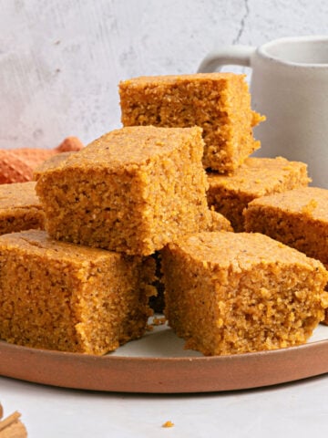Clay white plate with stacked sweet potato cornbread squares. Gray background.
