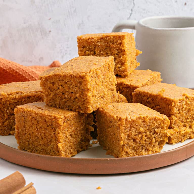 Clay white plate with stacked sweet potato cornbread squares. Gray background.