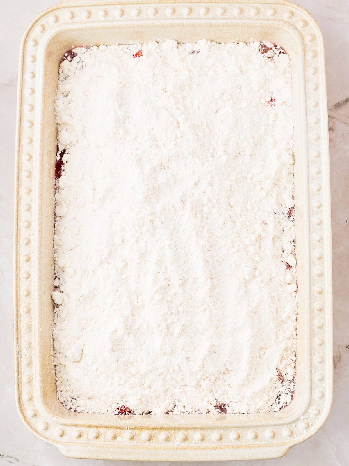 Cream-colored baking dish with cake mix topping.