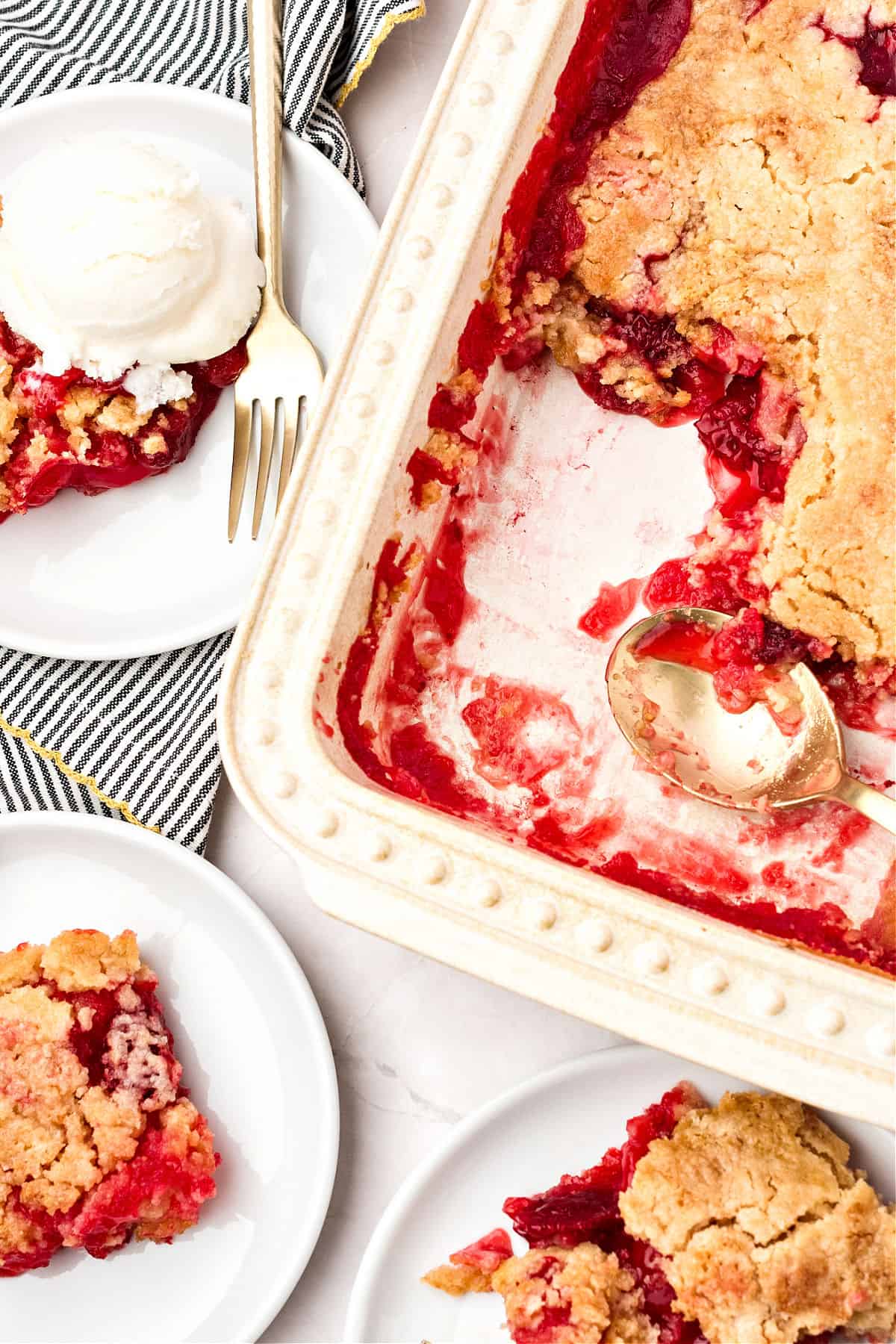 Baking dish with pineapple strawberry cobbler. White plates with servings.