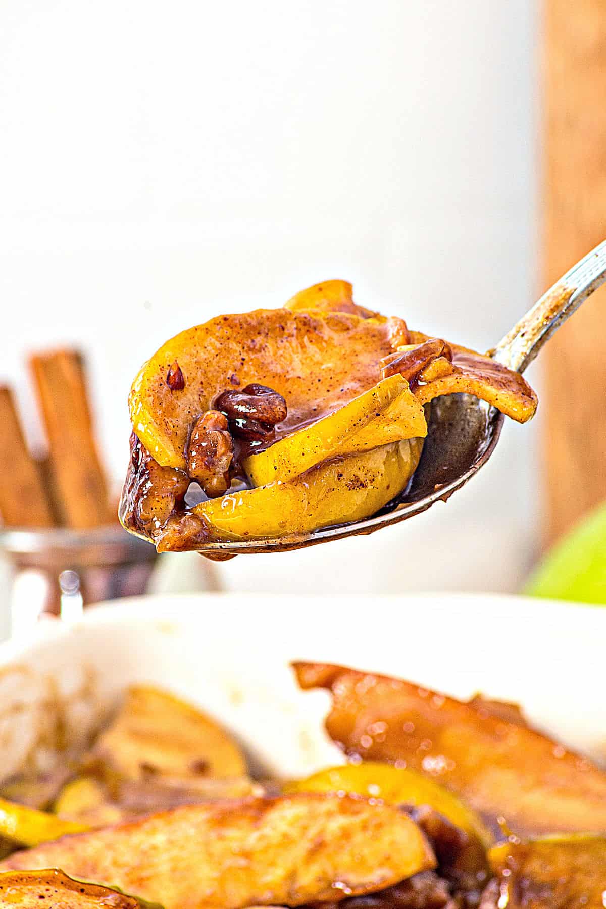 Silver spoon with bite of bakes apple wedges with cinnamon and pecans.