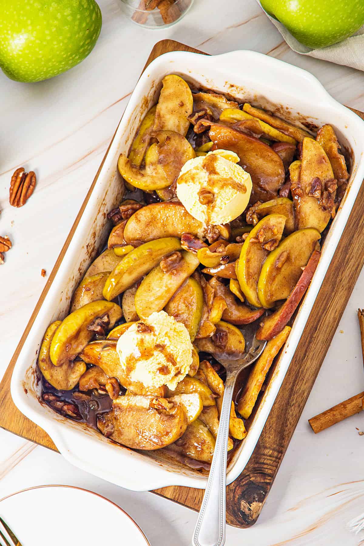 Top view of white dish with baked apple wedges and ice cream. White background.