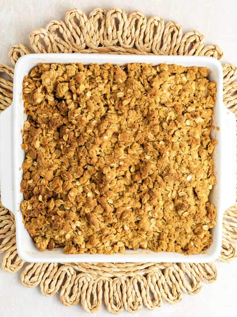 Raffia place holder with white dish of baked pear crisp on top.