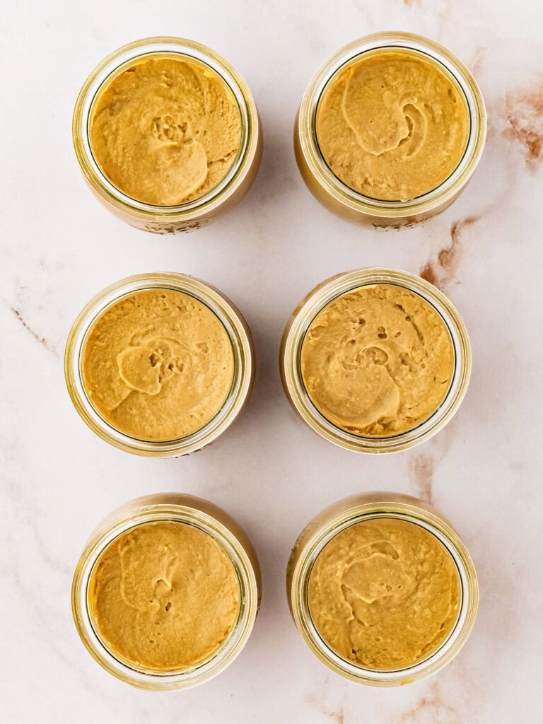 Six jars of butterscotch puddings. Marbled background. 