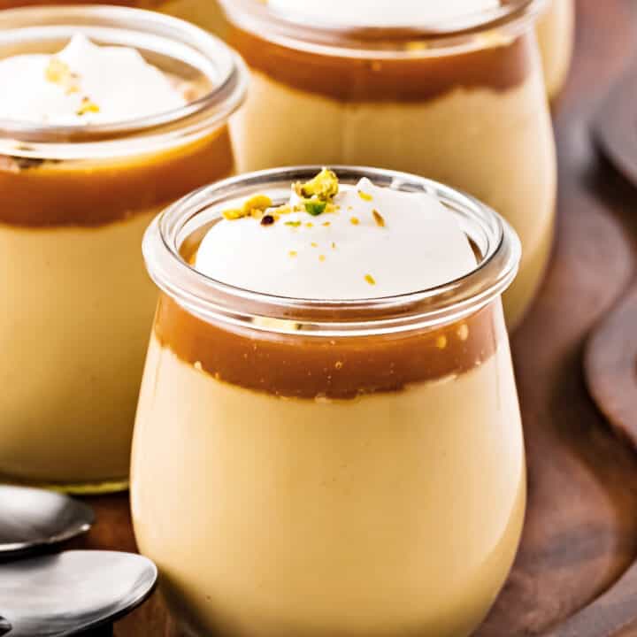 Close up jars of butterscotch, caramel and cream pudding. Wood surface.