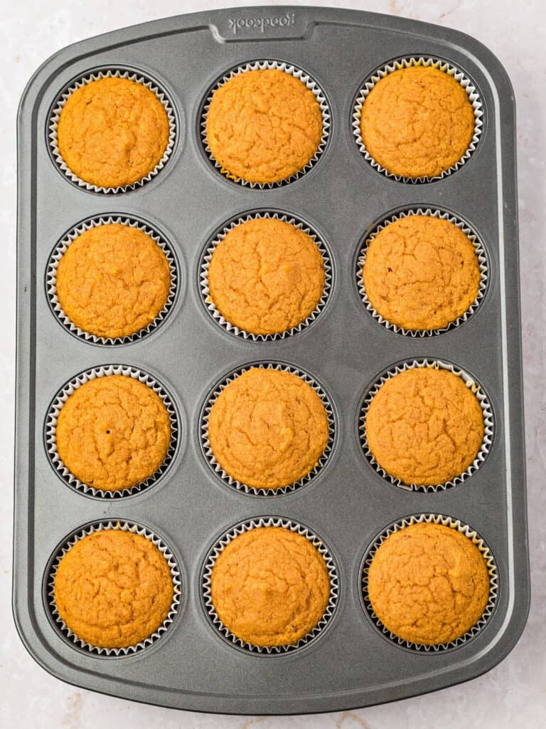 Baked cornbread muffins with pumpkin in a dark gray metal pan.