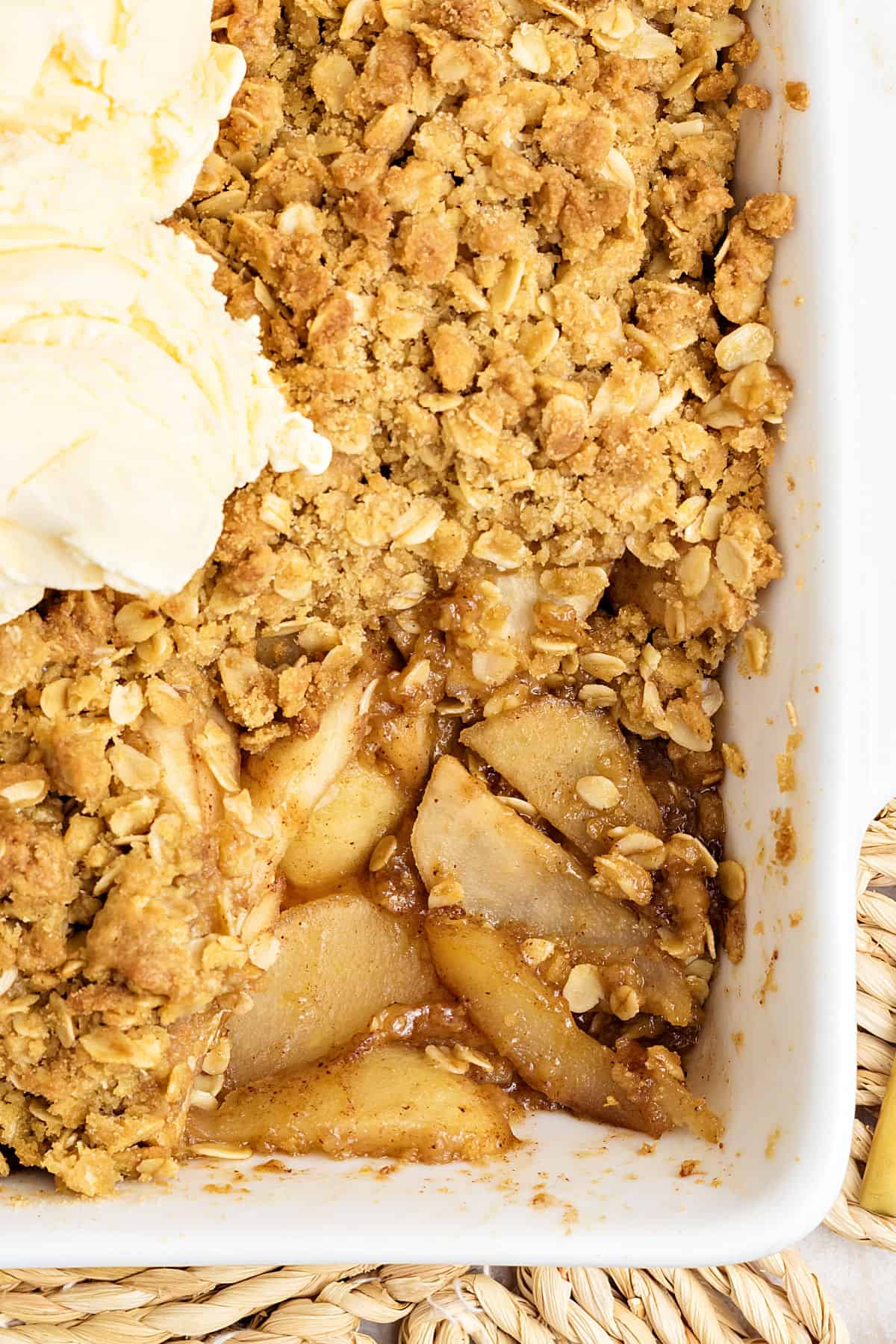 Rectangular white dish with pear crisp and ice cream scoops. Partial view.