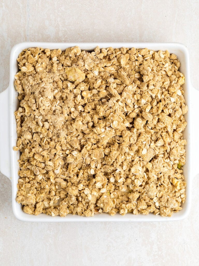 Oat crumble topping on square white dish. Light gray background.
