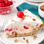 Creamy slice of millionaire pie. White plate, maraschino cherries, pecans. Teal kitchen towel.