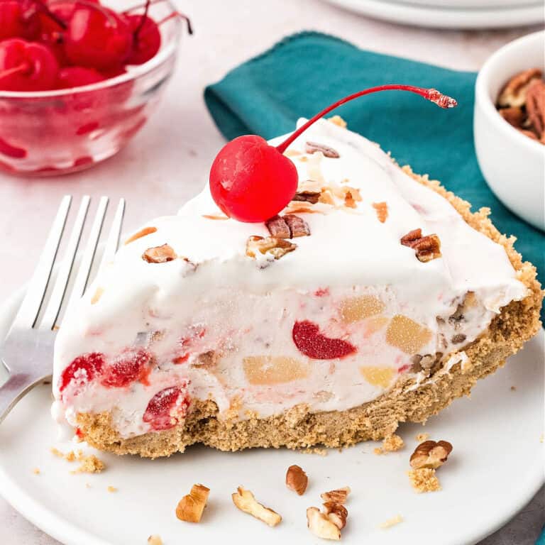 Creamy slice of millionaire pie. White plate, maraschino cherries, pecans. Teal kitchen towel.