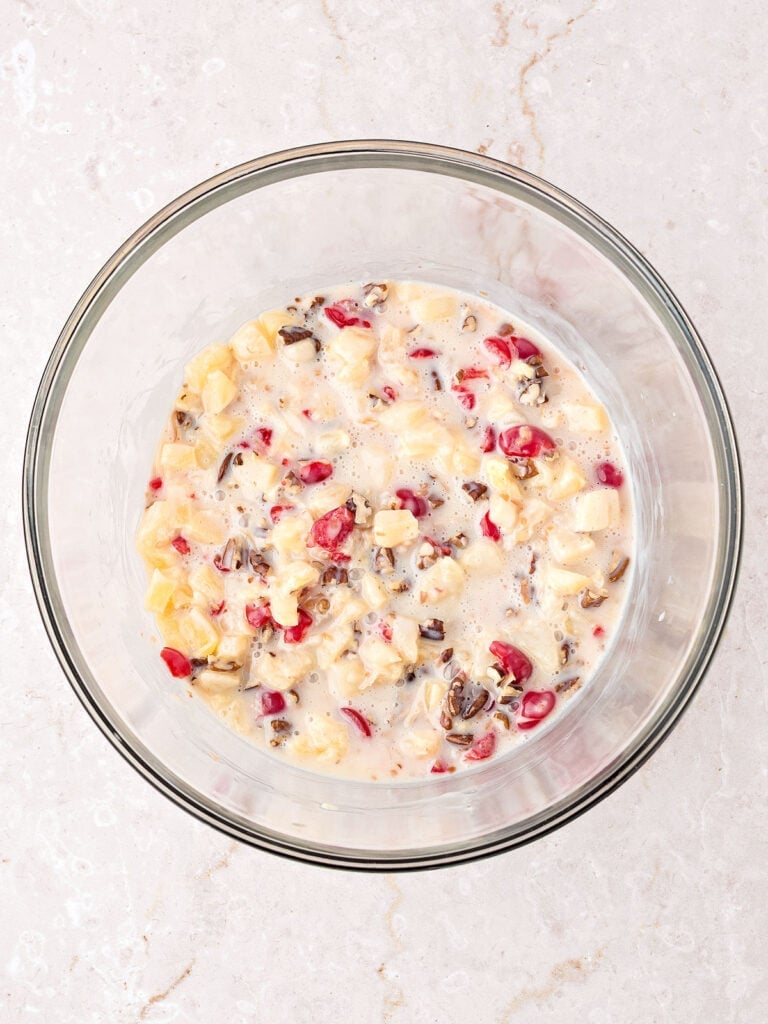 Condensed milk with cherries, pineapple and pecans in a glass bowl. Marbled background.