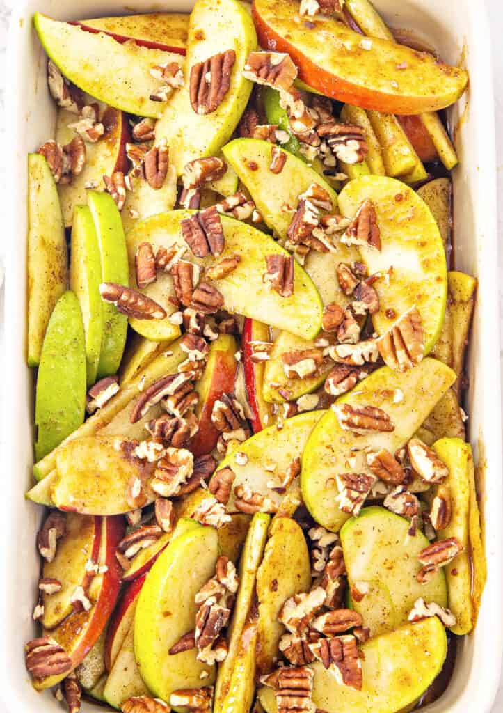 Chopped pecans on spiced apple wedges before baking.